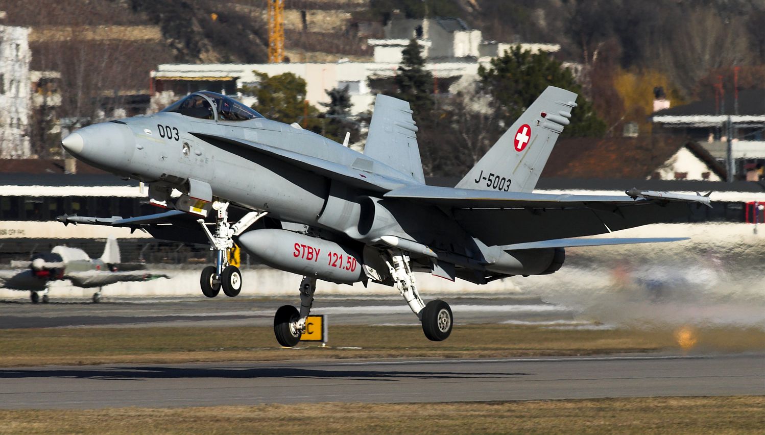 Dipinta in caratteri ben visibili sul serbatoio ventrale degli Hornet, la frequenza di allerta in uso nello spazio aereo di Davos F-18C in decollo